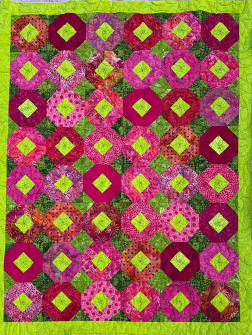 Grafisk tæppe med håndbroderi og åbent blomster quiltemønster i hot pink
